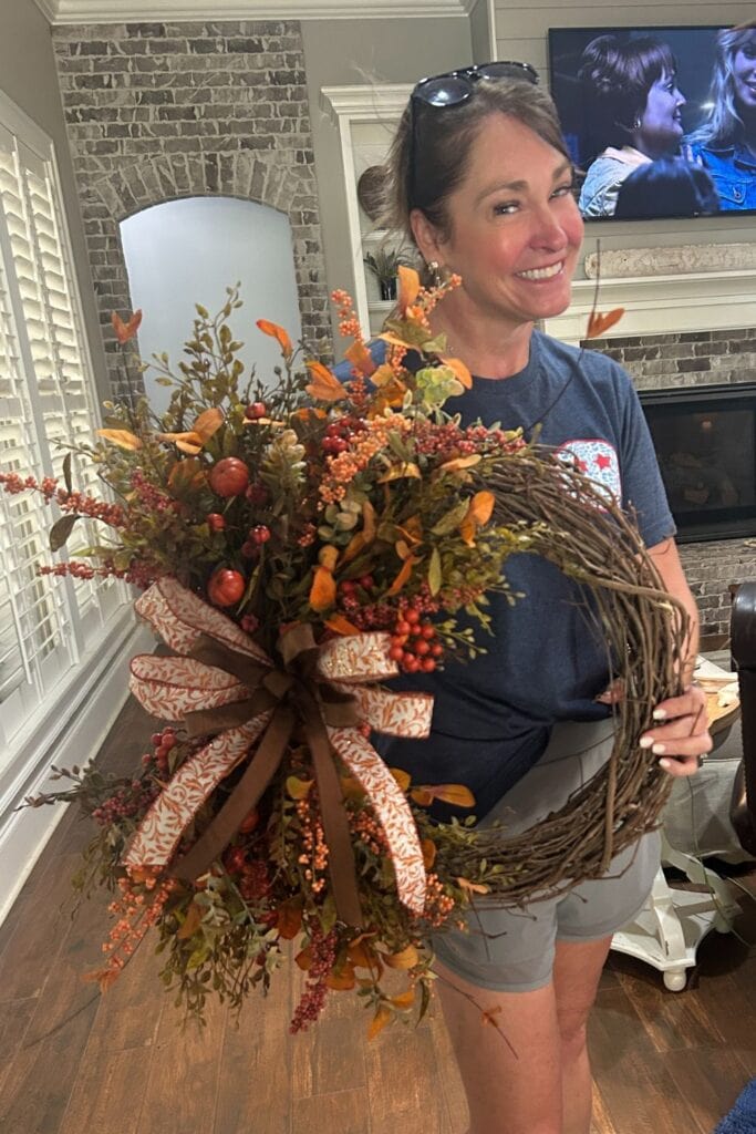 daughter Carrie with fall florals on a grapevine wreath with simple bow