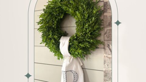 green boxwood wreath with a monogrammed tea towel used as a wreath sash