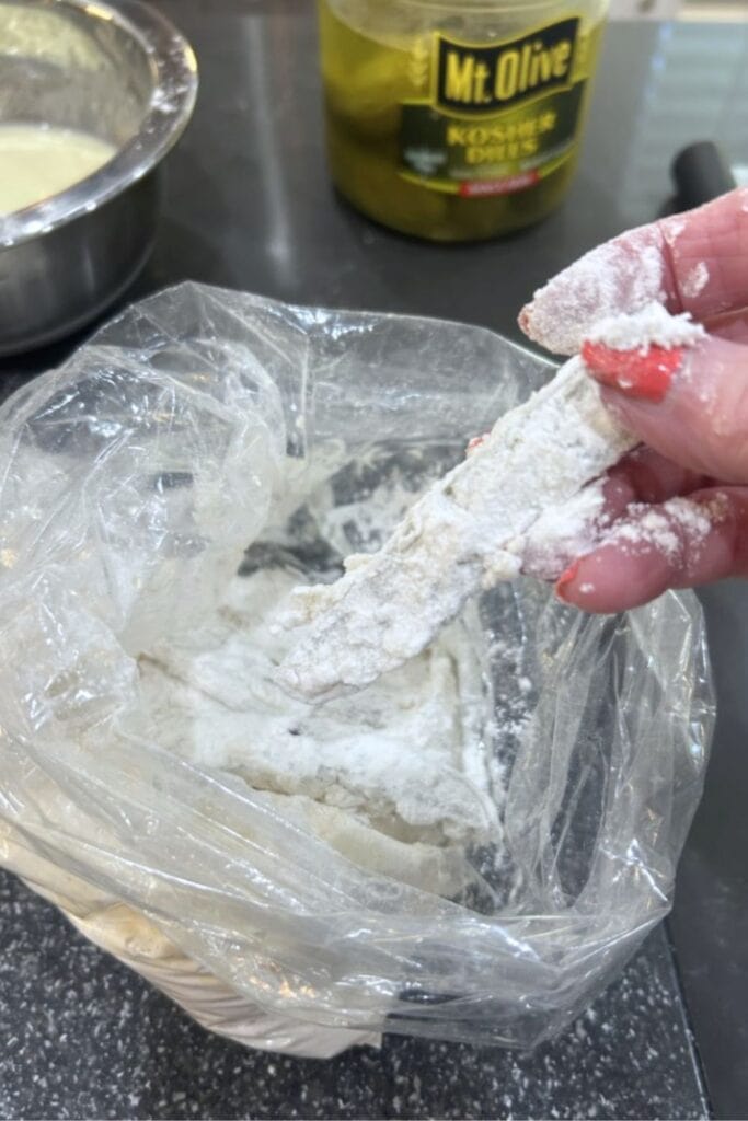 dill pickle slices having been coated in corn starch, dipped in egg/buttermilk/seasoning mixture and battered with flour