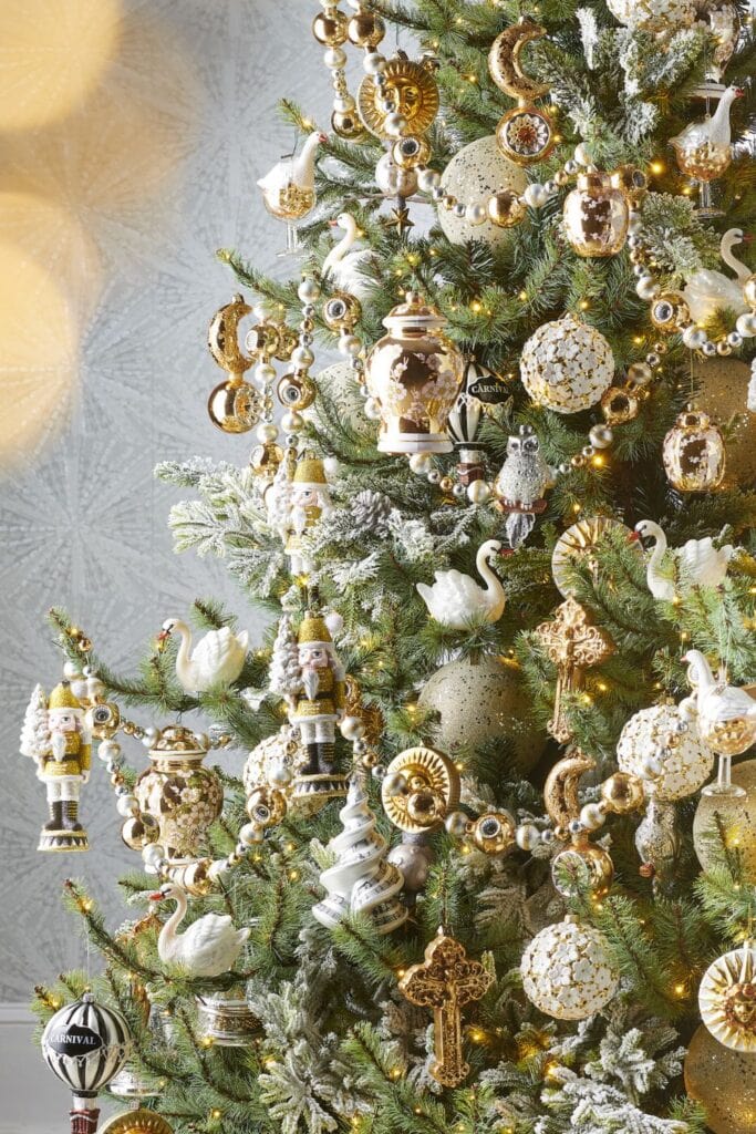 Christmas tree decorated in gold and ivory with swan ornaments, nutcrackers, celestial sun and moon ornaments, and elegant glass garlands in the Eric Cortina style.