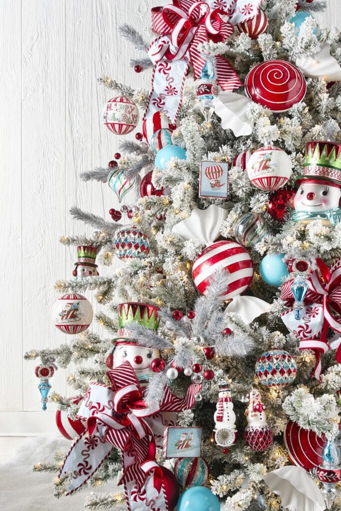 Flocked RAZ Christmas tree decorated with snowman ornaments, red and white ribbon, peppermint accents, and vintage-style glass ornaments in red, aqua, and silver.